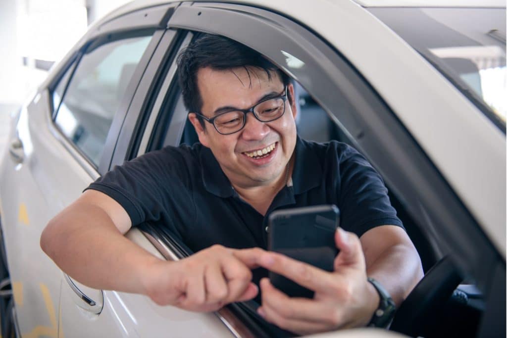 Uber Driver leaning out the car window using his phone